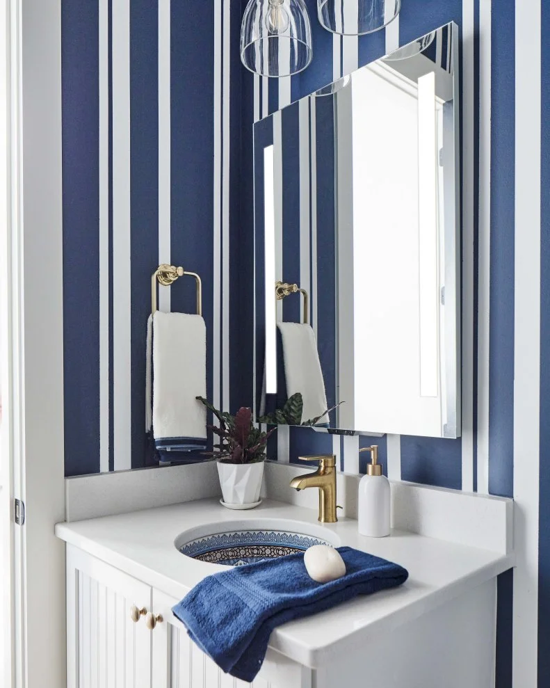 With bold striped walls and user-friendly features, this powder room located on the first floor of HGTV Smart Home 2022 reflects the contemporary style of this sophisticated and timeless waterside retreat.